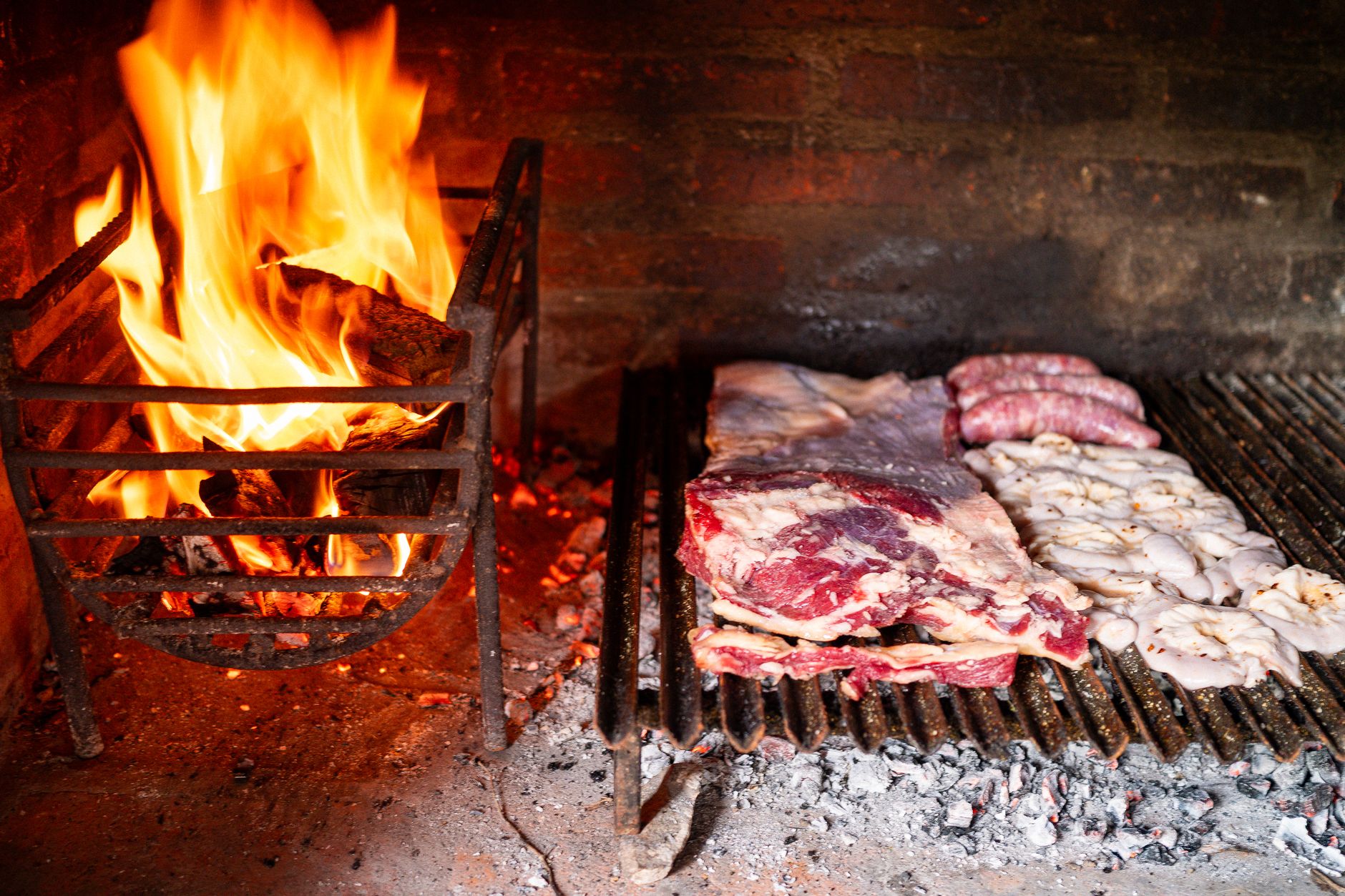 Mesa servida con copas de vino tinto y asado argentino